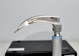 Ветеринарний ларингоскоп з клинком Macintosh у зборі, встановлений на рукоятку, на фоні чорного пластикового кейсу для зберігання